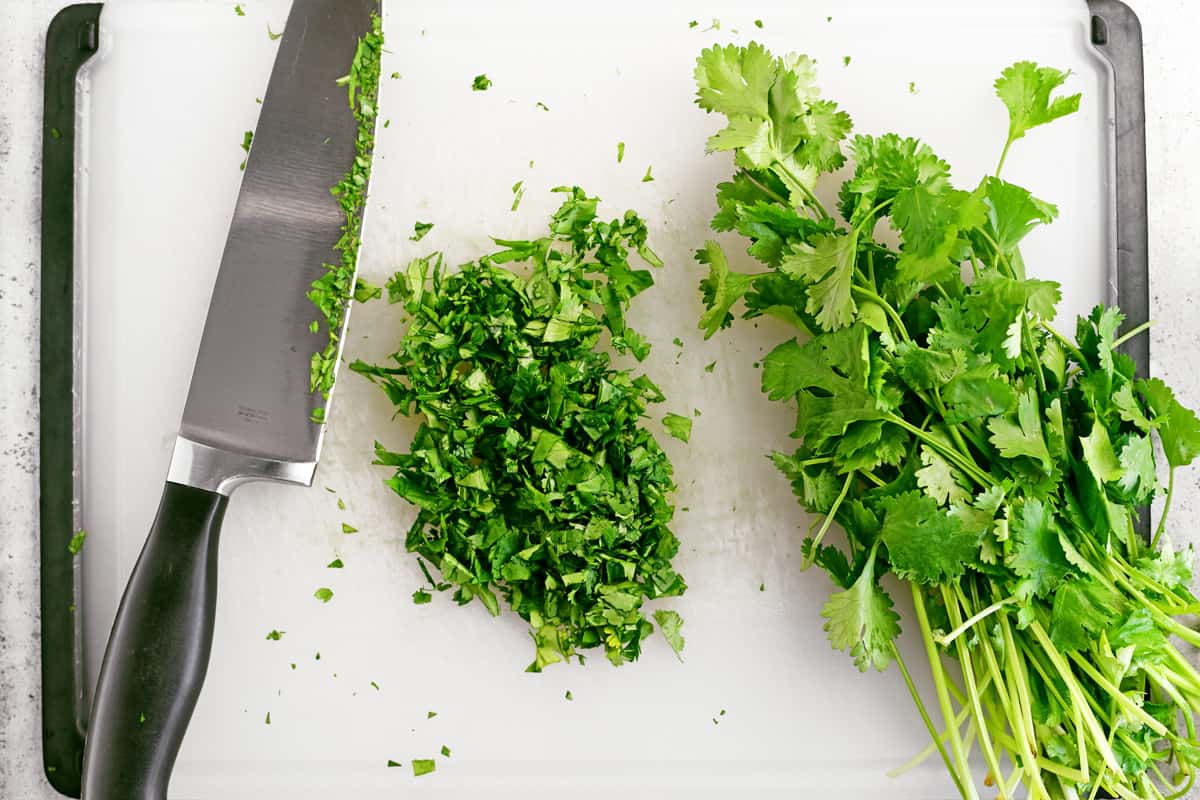Chopped cilantro and a knife on a cutting board.