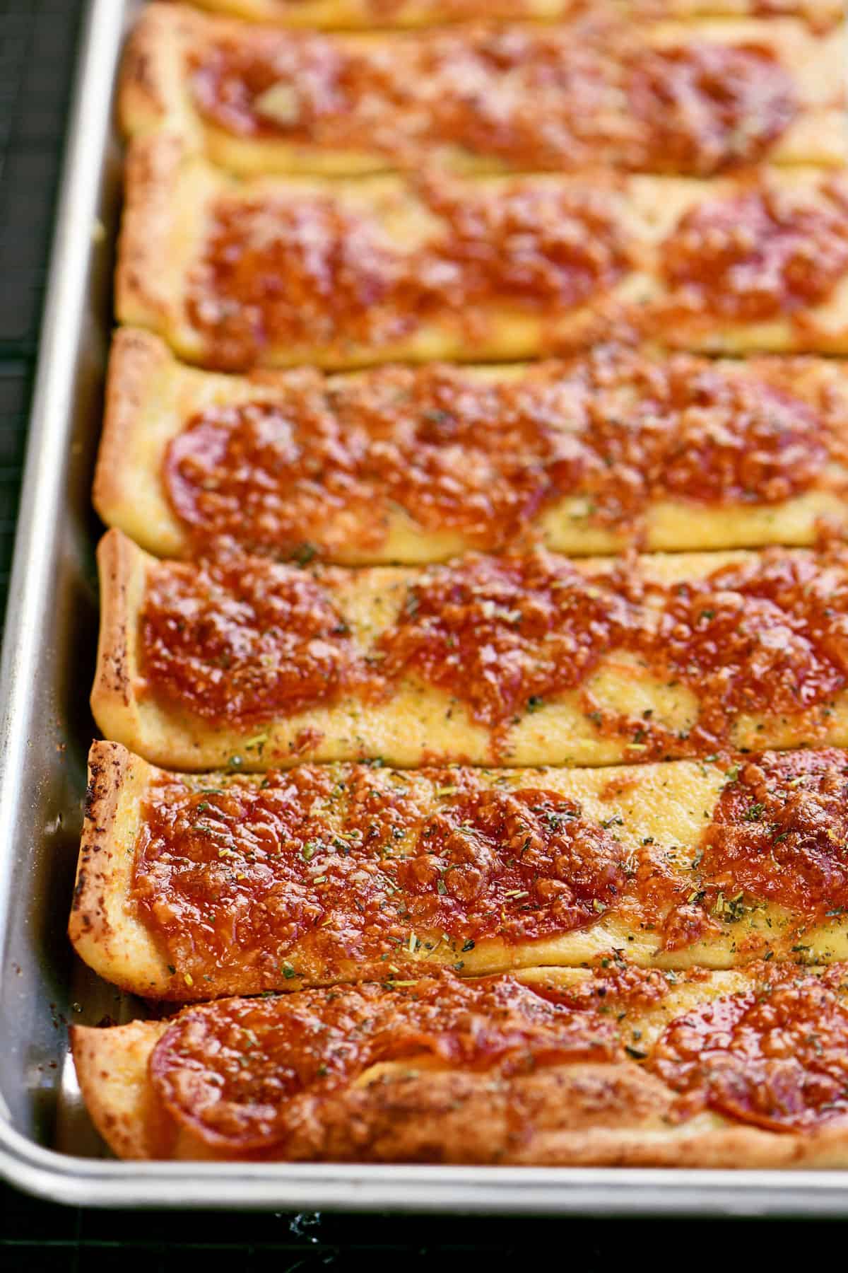 Pizza sticks lined up in a row on a pan.
