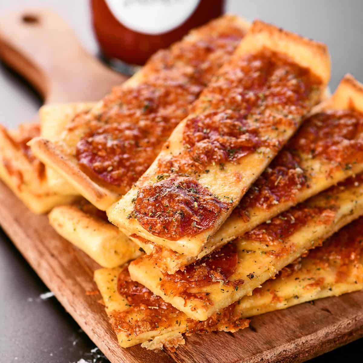 A pile of pizza sticks on a cutting board.