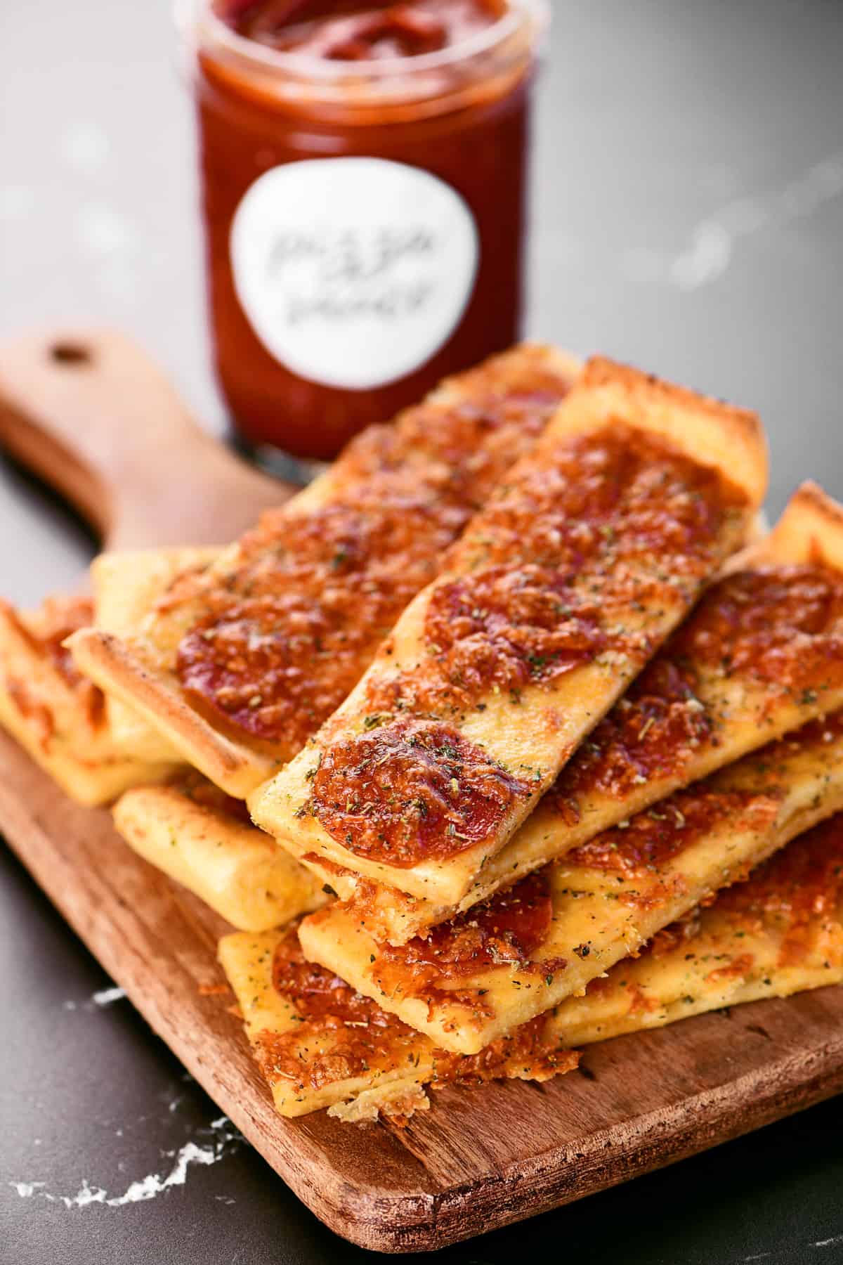 Pizza Sticks piled up on a wooden serving board.