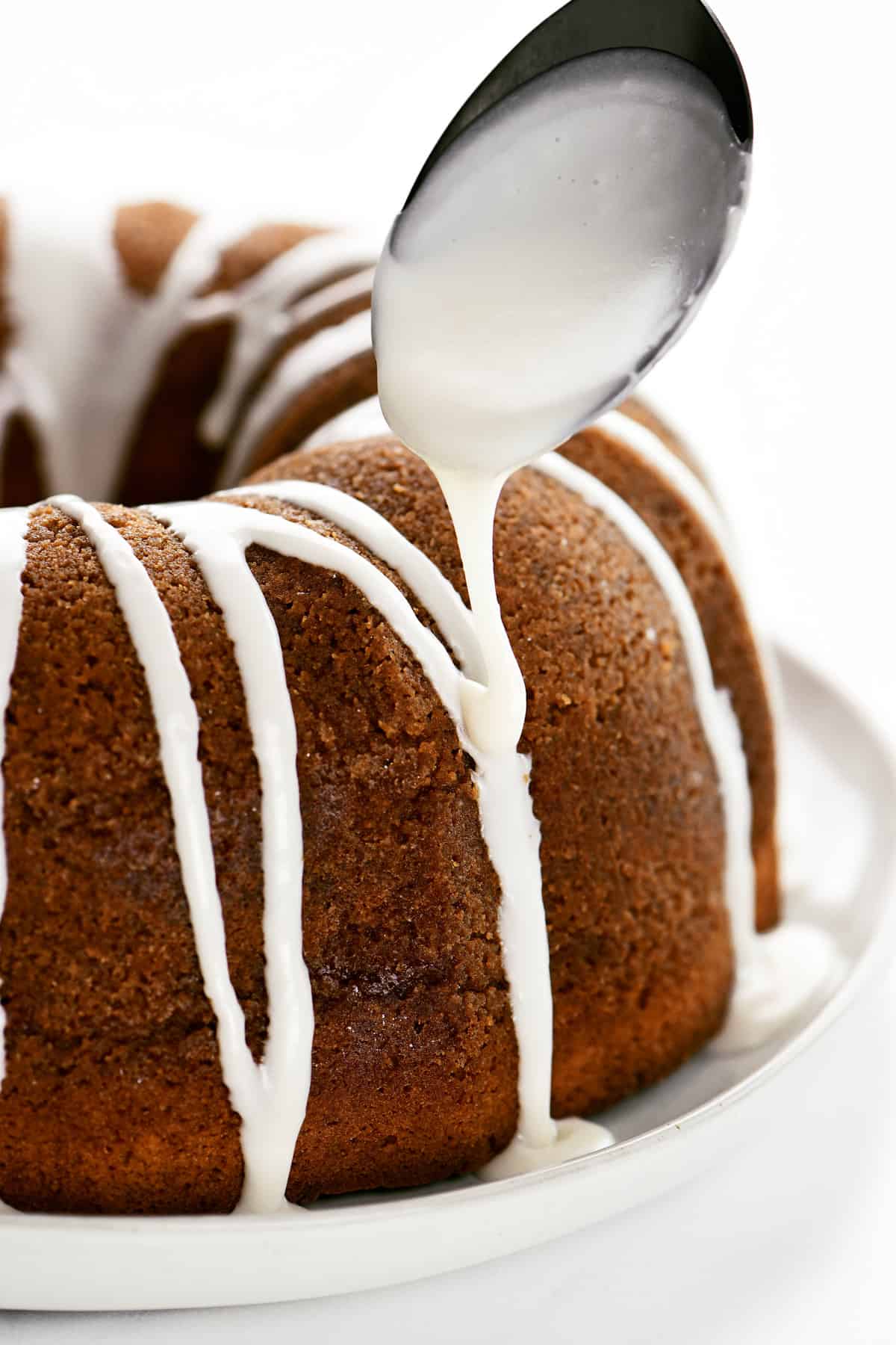 Powdered sugar icing being drizzled onto a bundt cake.