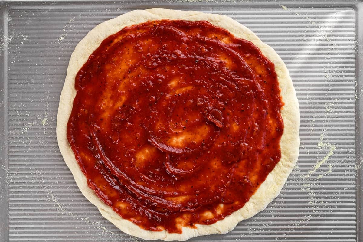 BBQ sauce pizza on a baking sheet.
