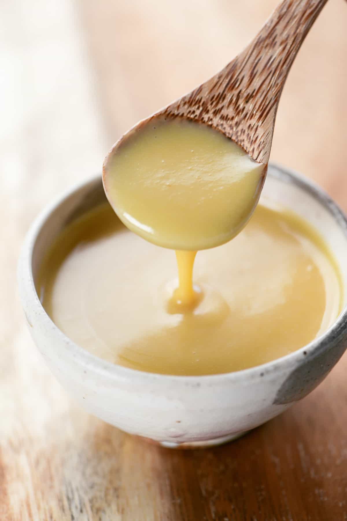 Spicy Honey Mustard sauce drizzled from a wooden spoon into a bowl.