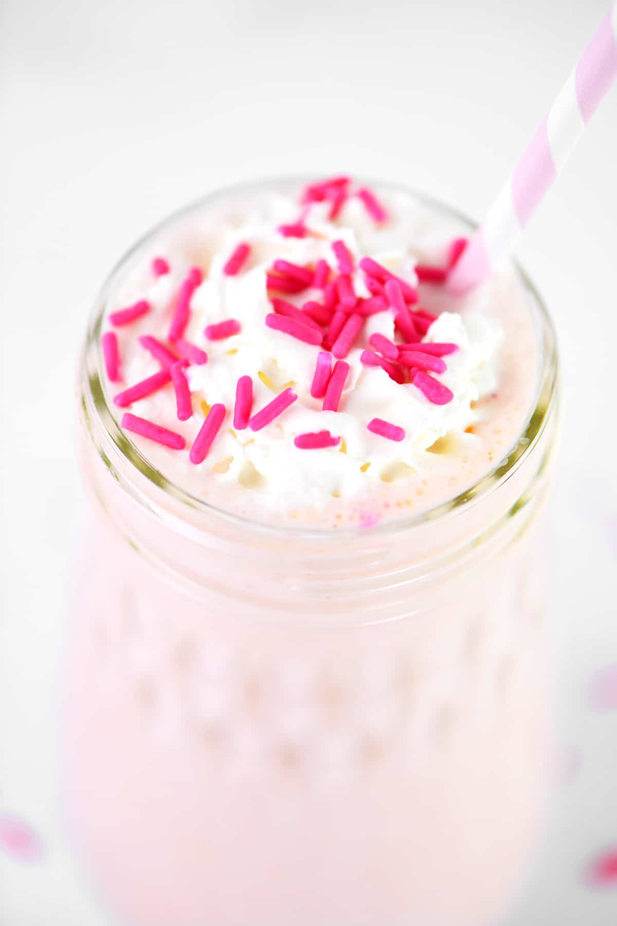 pink sprinkles and whipped cream on a strawberry shake.