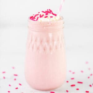 A strawberry milkshake in a glass jar.