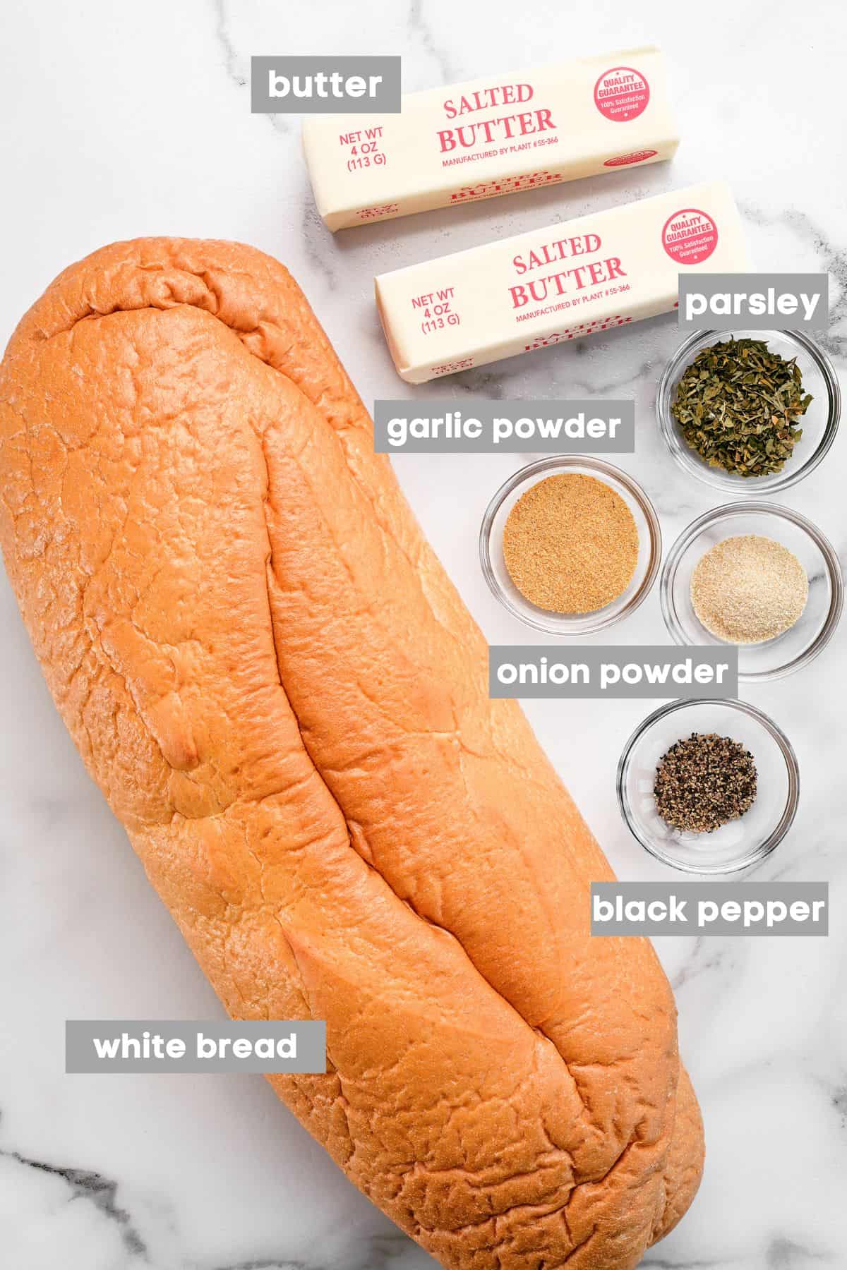 Bread and other ingredients on a white marble countertop.