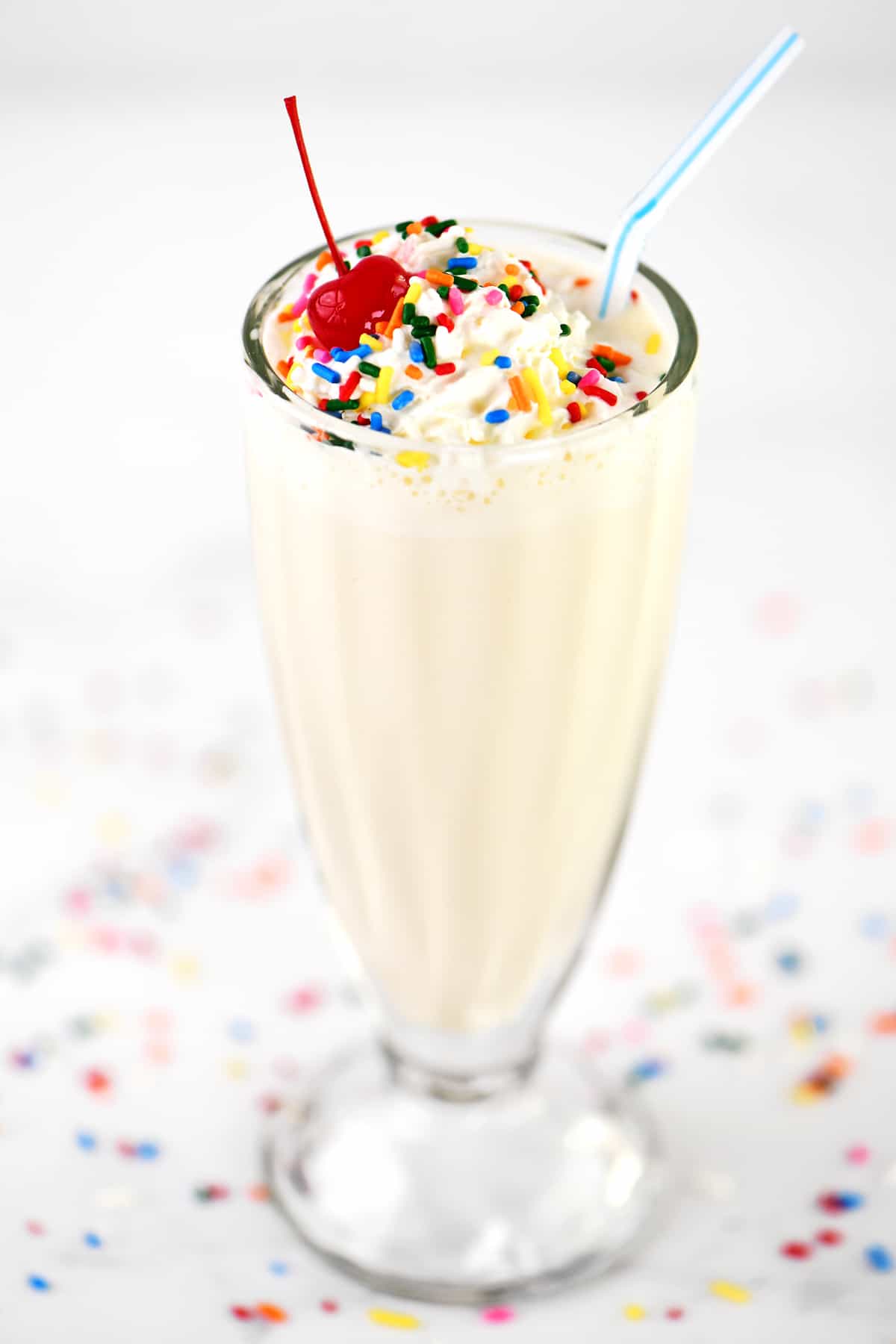 A malt glass with a vanilla milkshake inside.