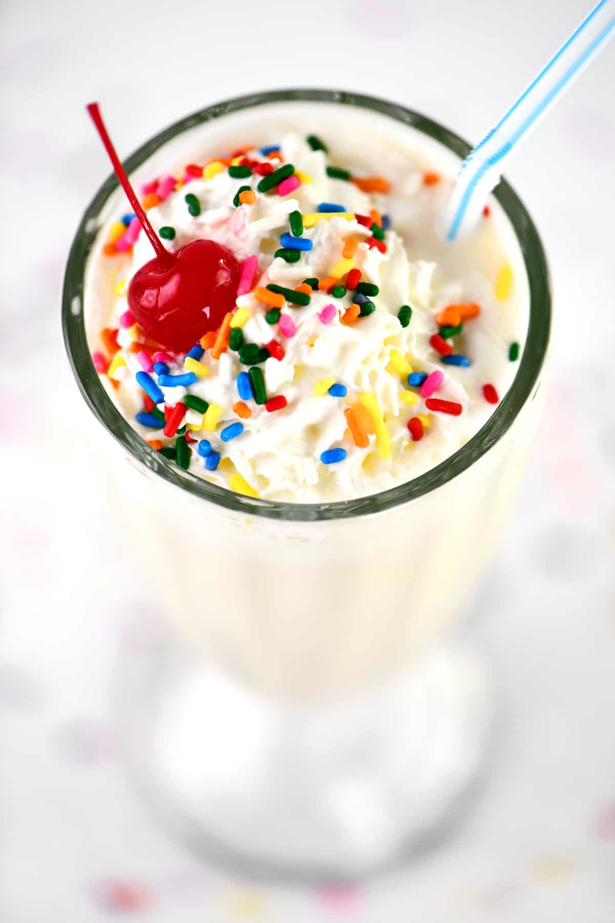 a cherry, sprinkles and whipped topping on a vanilla shake.