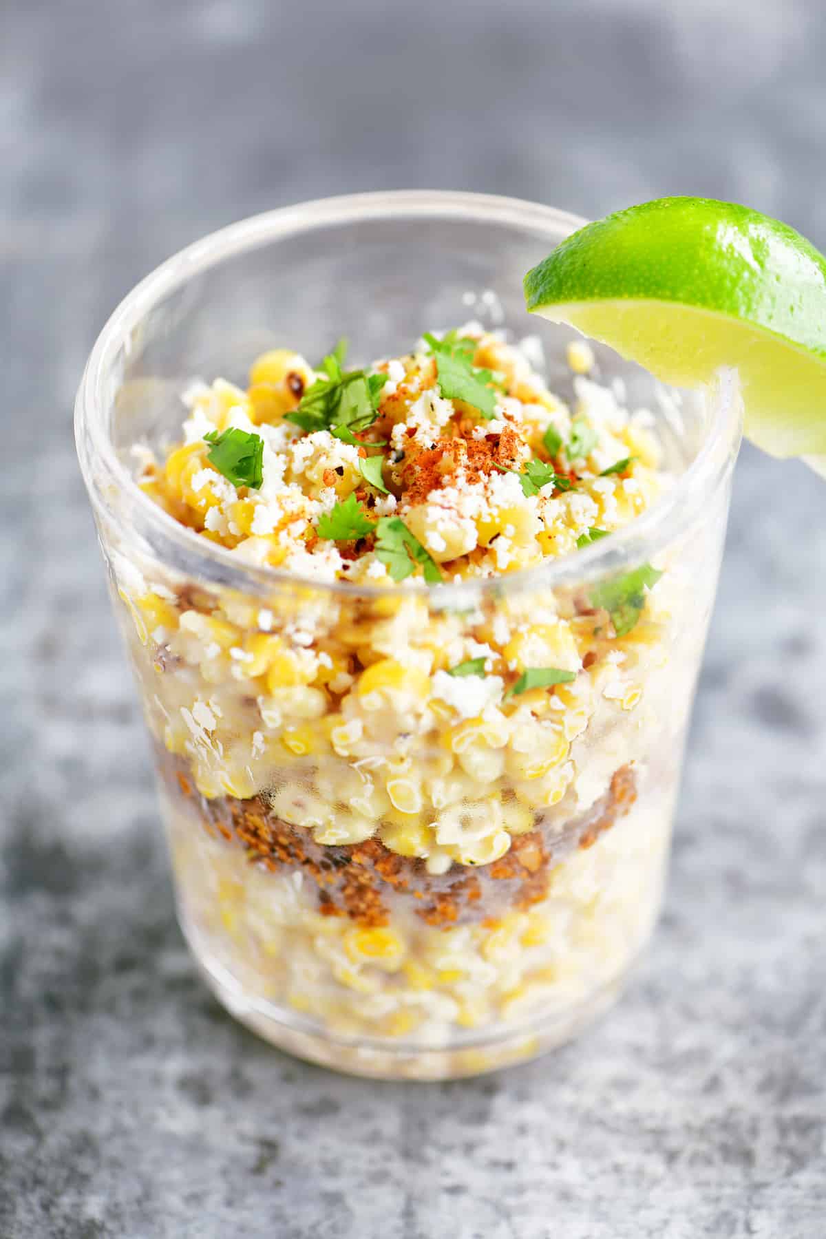 Esquites or corn a cup with a lime wedge.