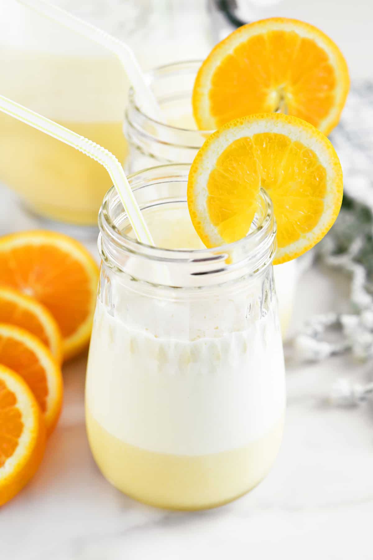 two cups of homemade orange julius garnished with orange slices