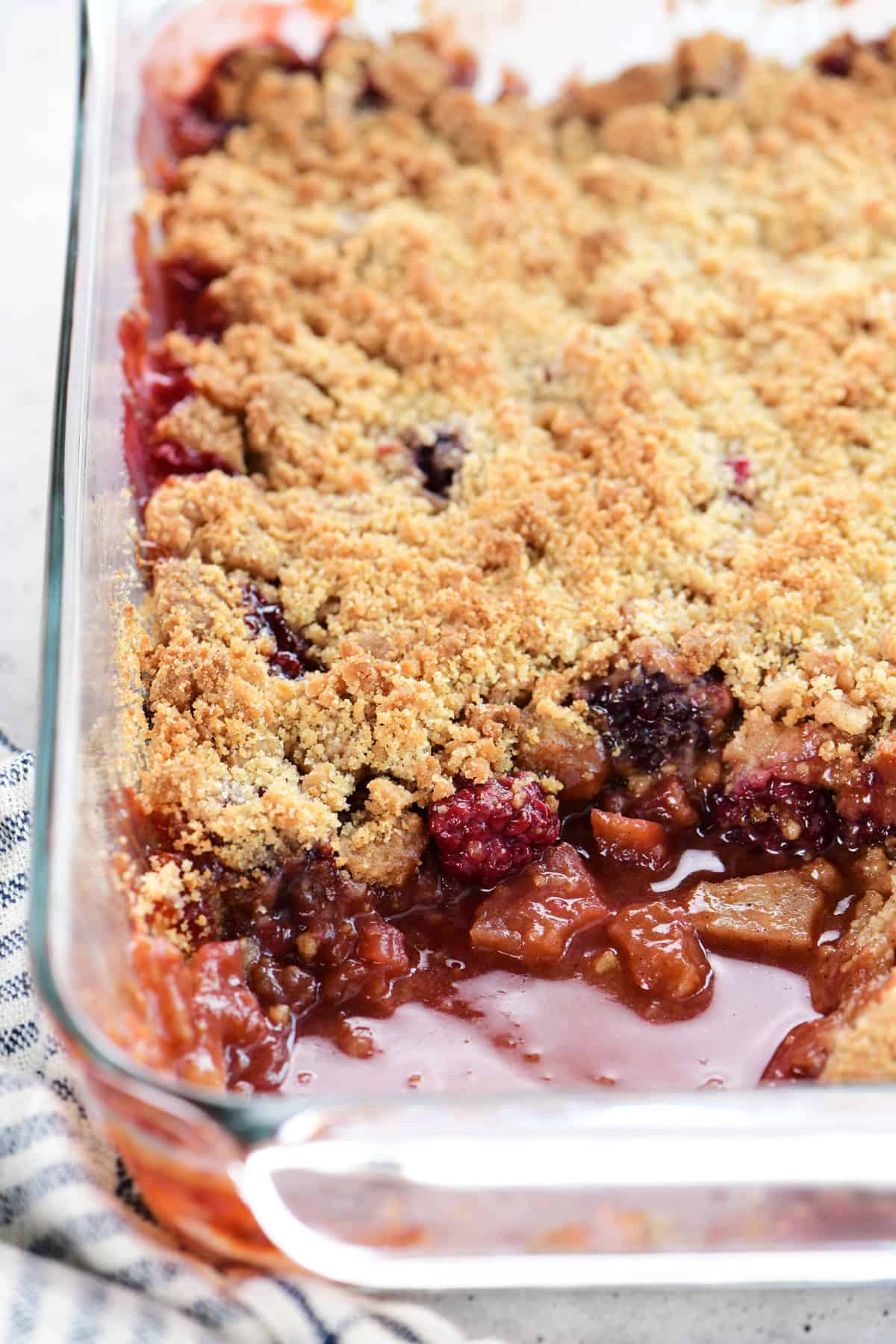 Cooked apple and blackberry crumble in pan.