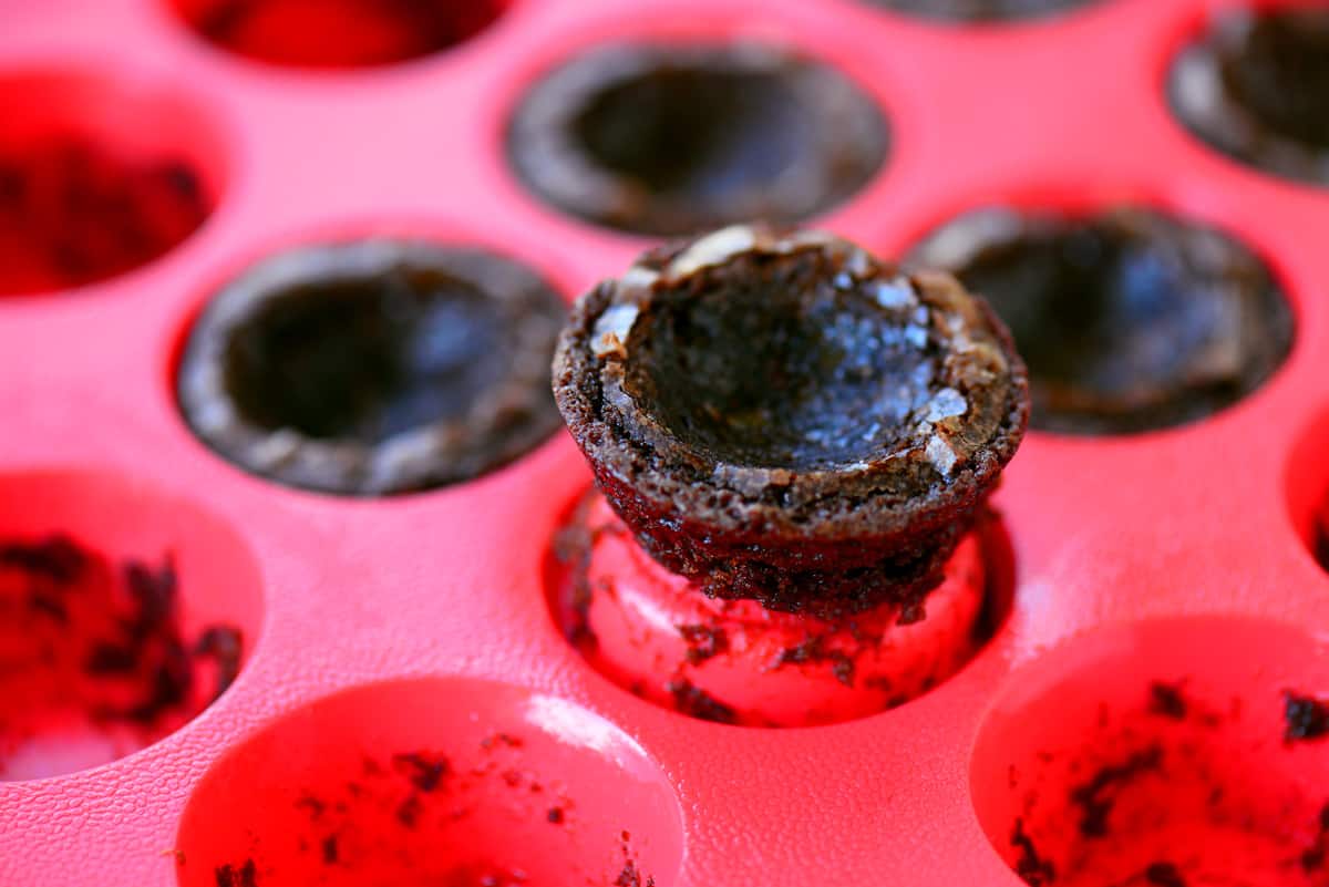 Removing a brownie bite from a pan.