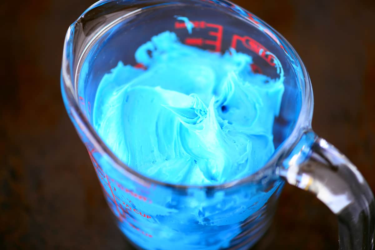 Blue frosting in a glass bowl.