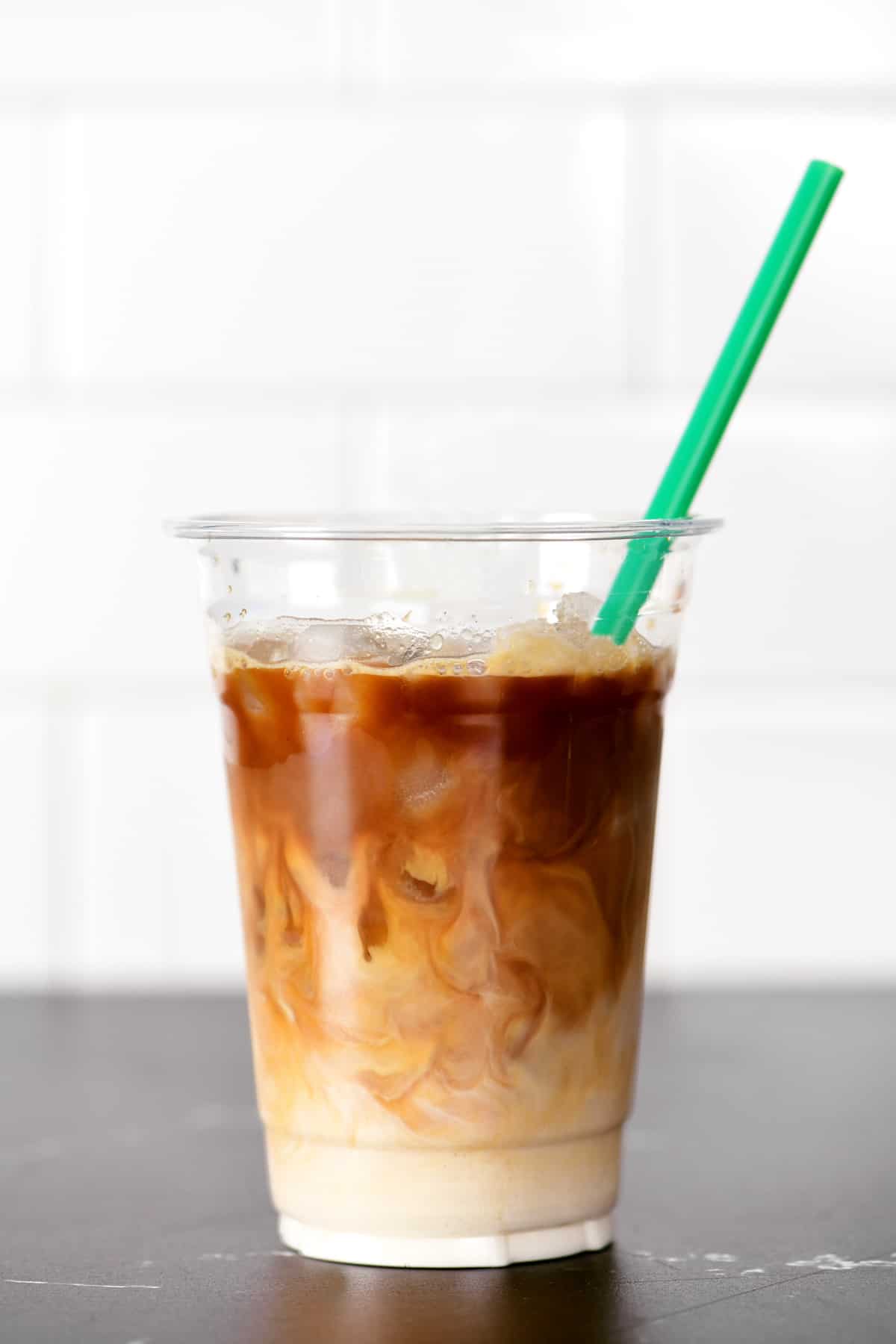 Iced coffee in a cup with a green straw.