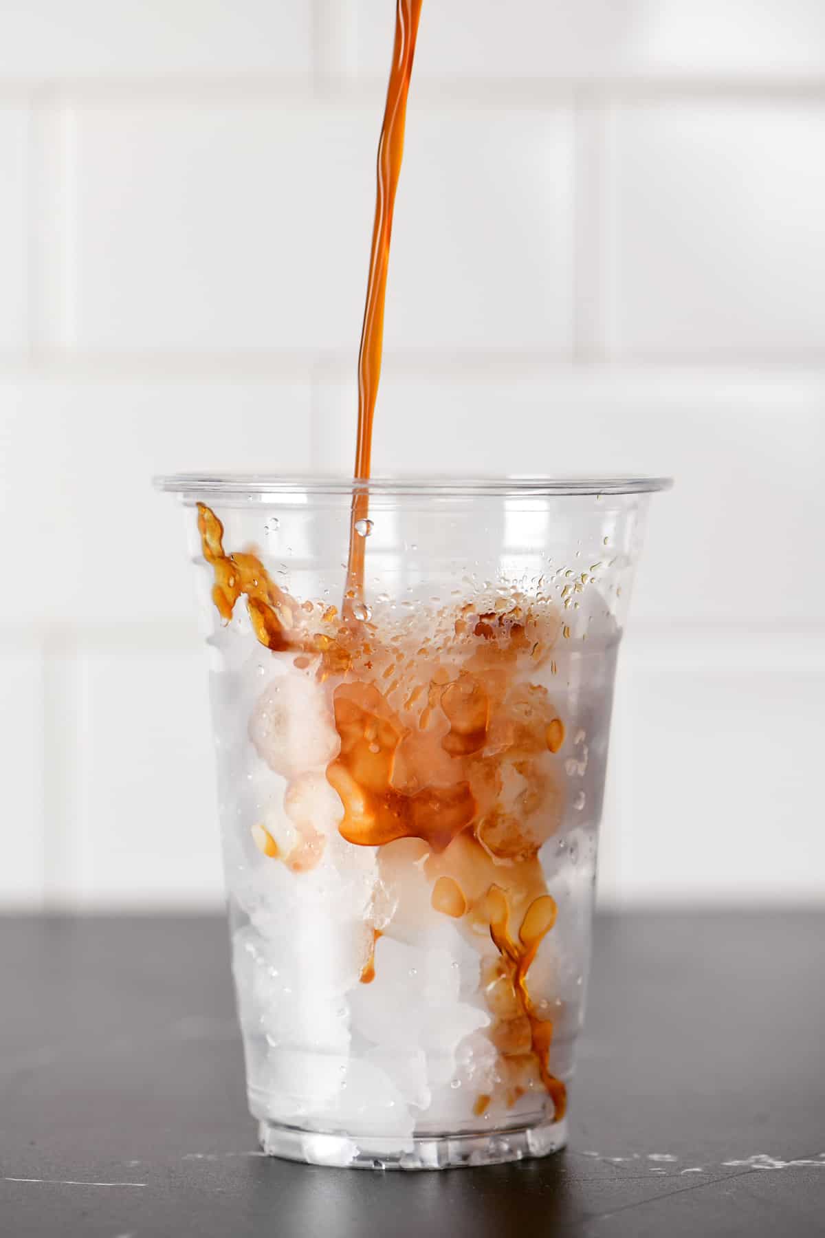 Espresso being poured over ice in a cup.