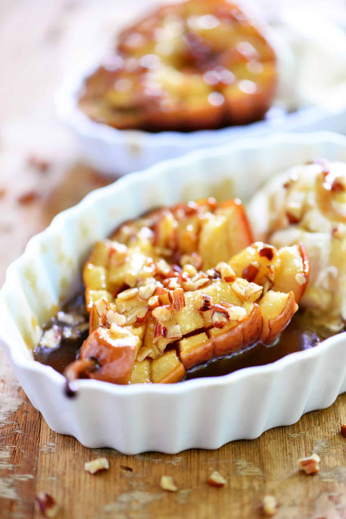 A baked pear in a bowl with nuts and caramel.