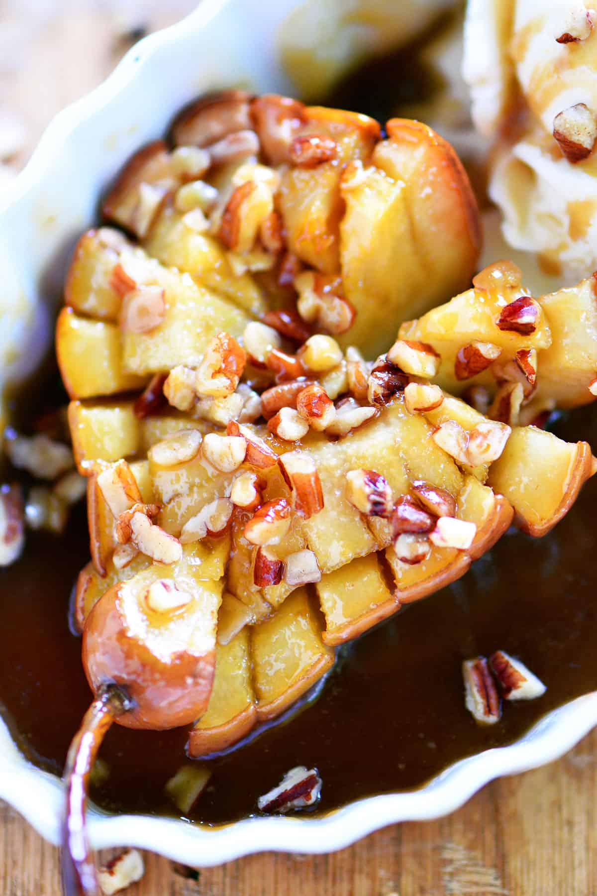 Chopped pecans on a caramel pear in a dish.