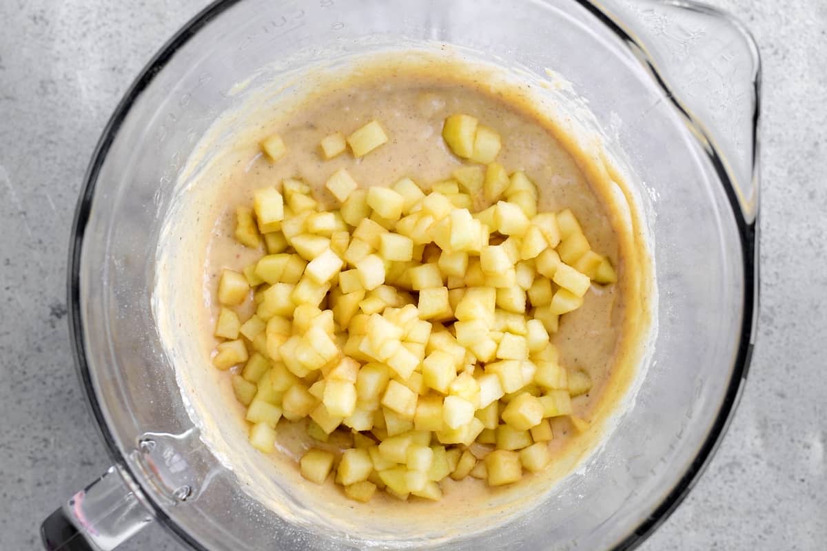 diced apples added to batter in bowl