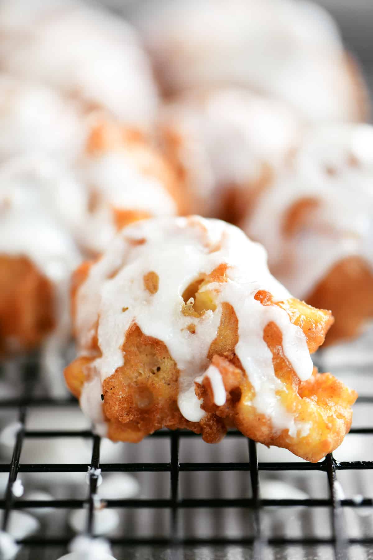 Glazed apple fritters on a wire rack.