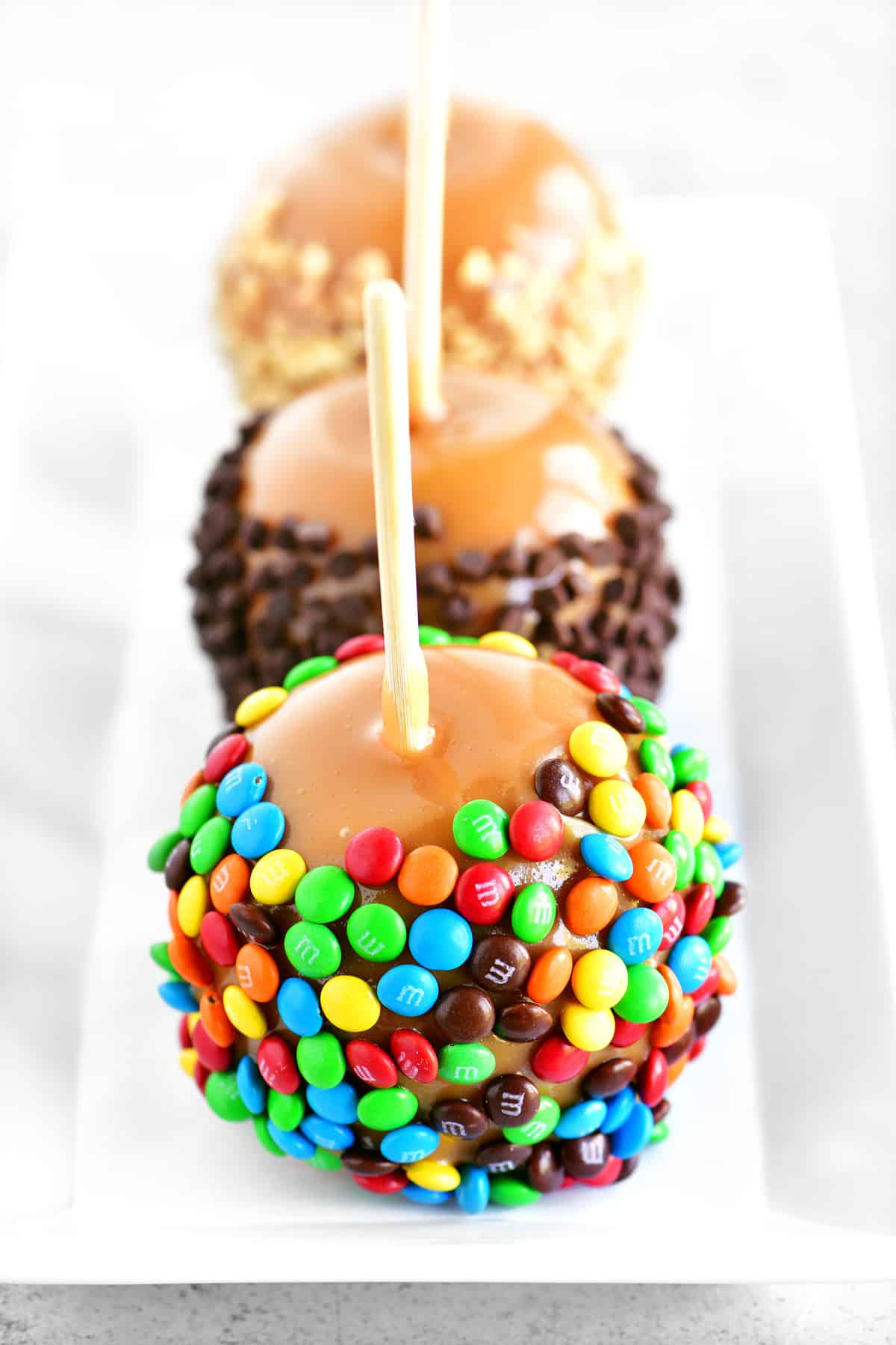 Three gourmet apples on a white tray.