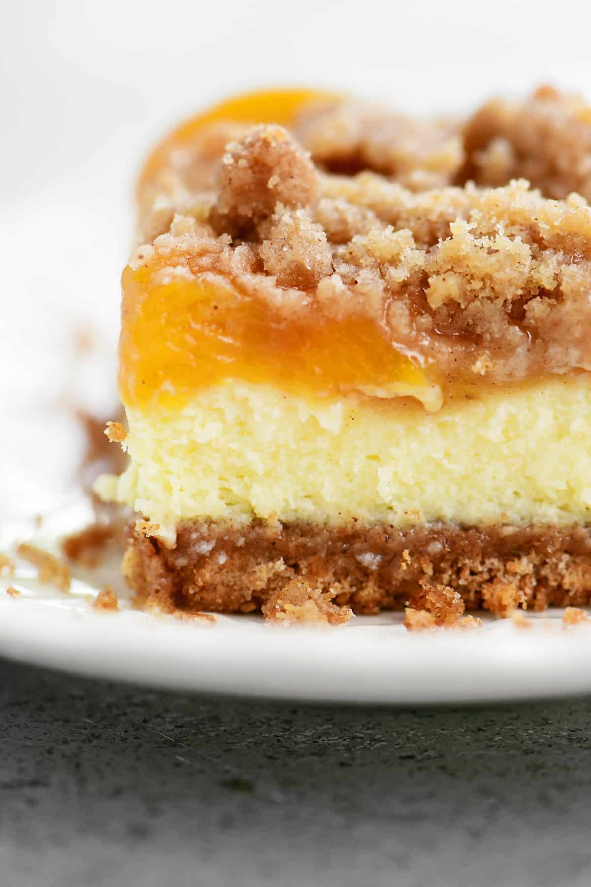 Peach cobbler cheesecake layers on a plate.