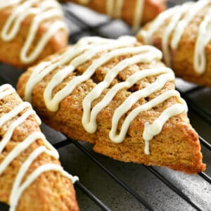 Frosted pumpkin scones on a wire rack.