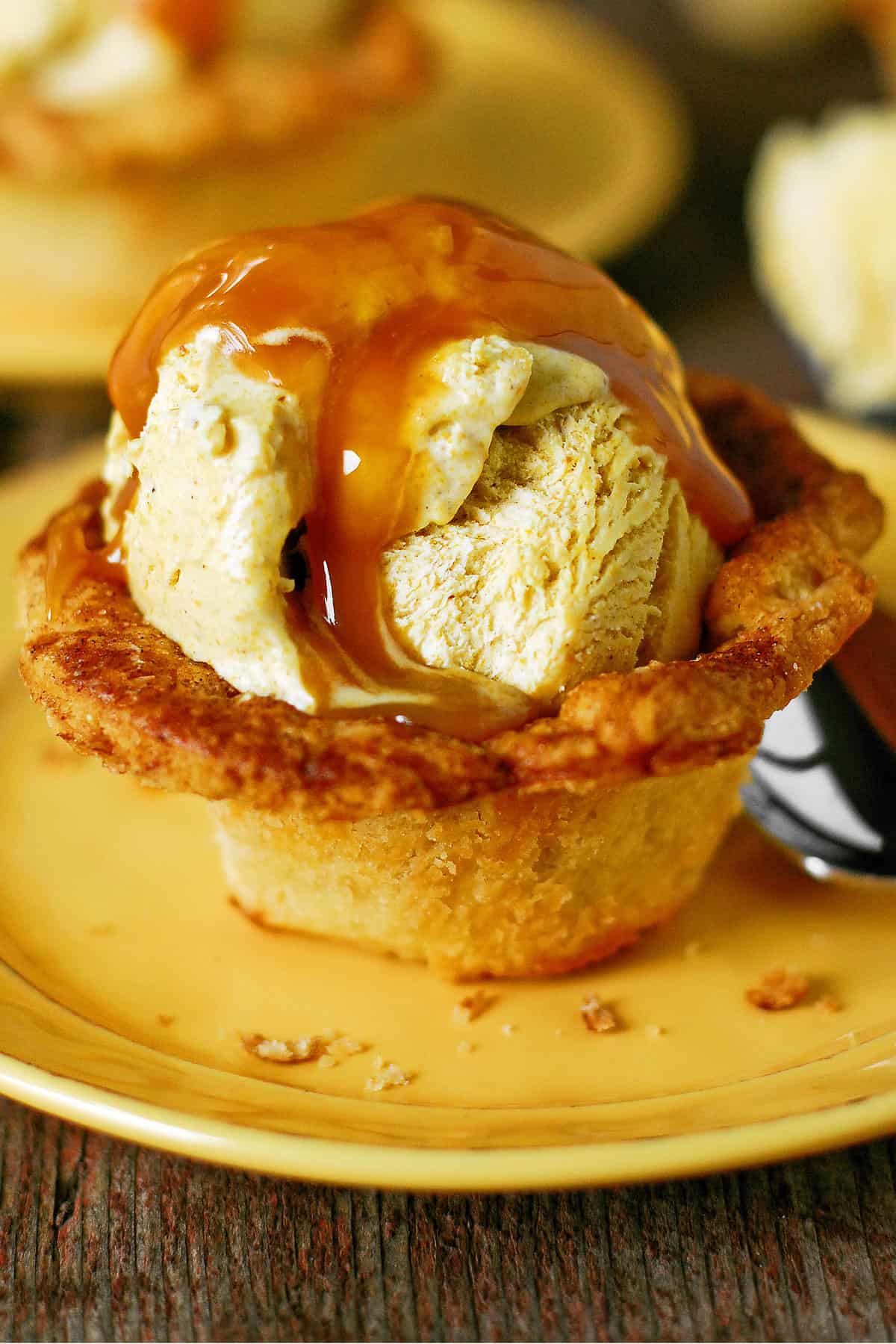 a pie crust cup with pumpkin ice cream and caramel inside.