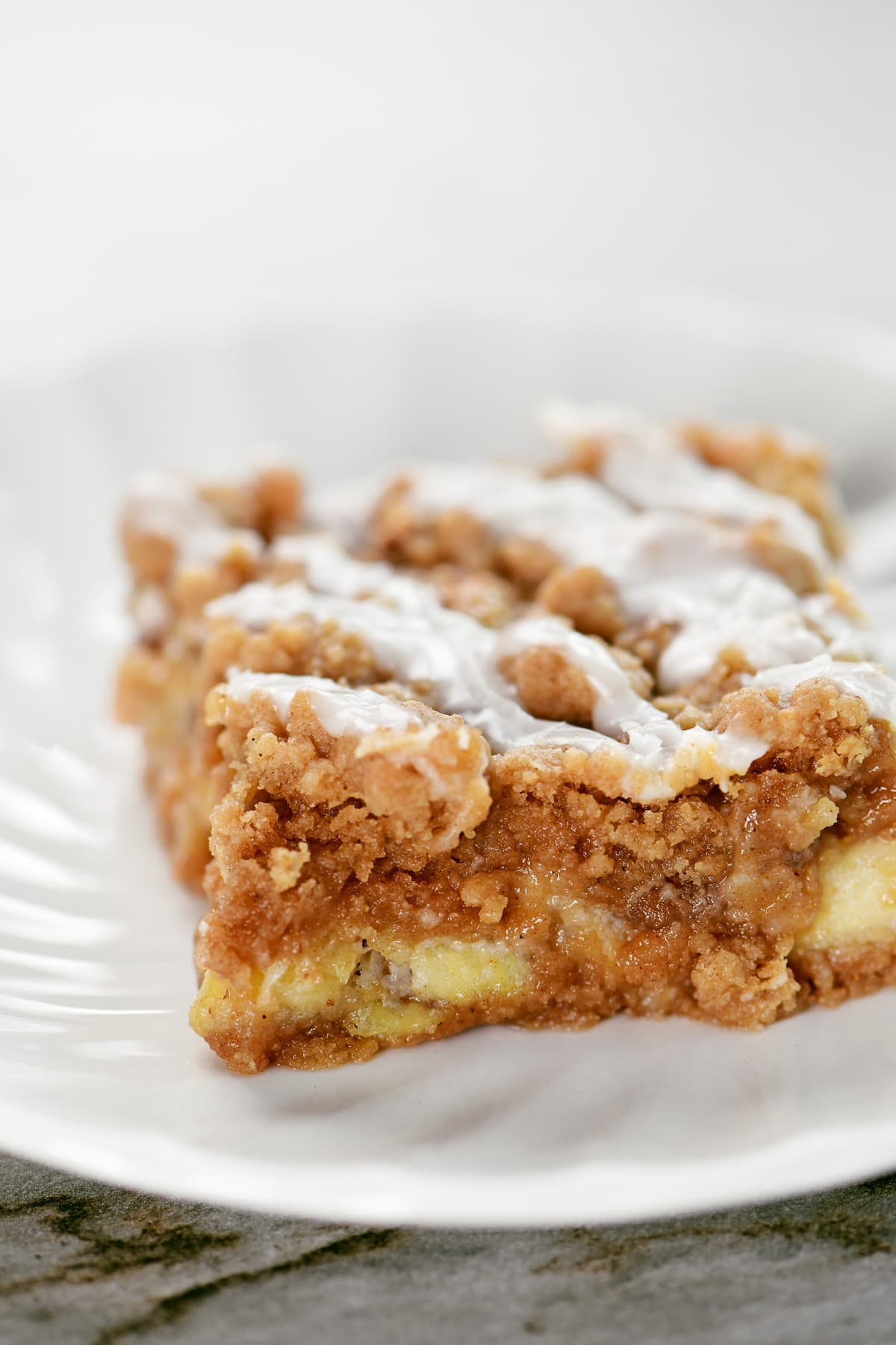 A slice of an apple bar with icing on top.