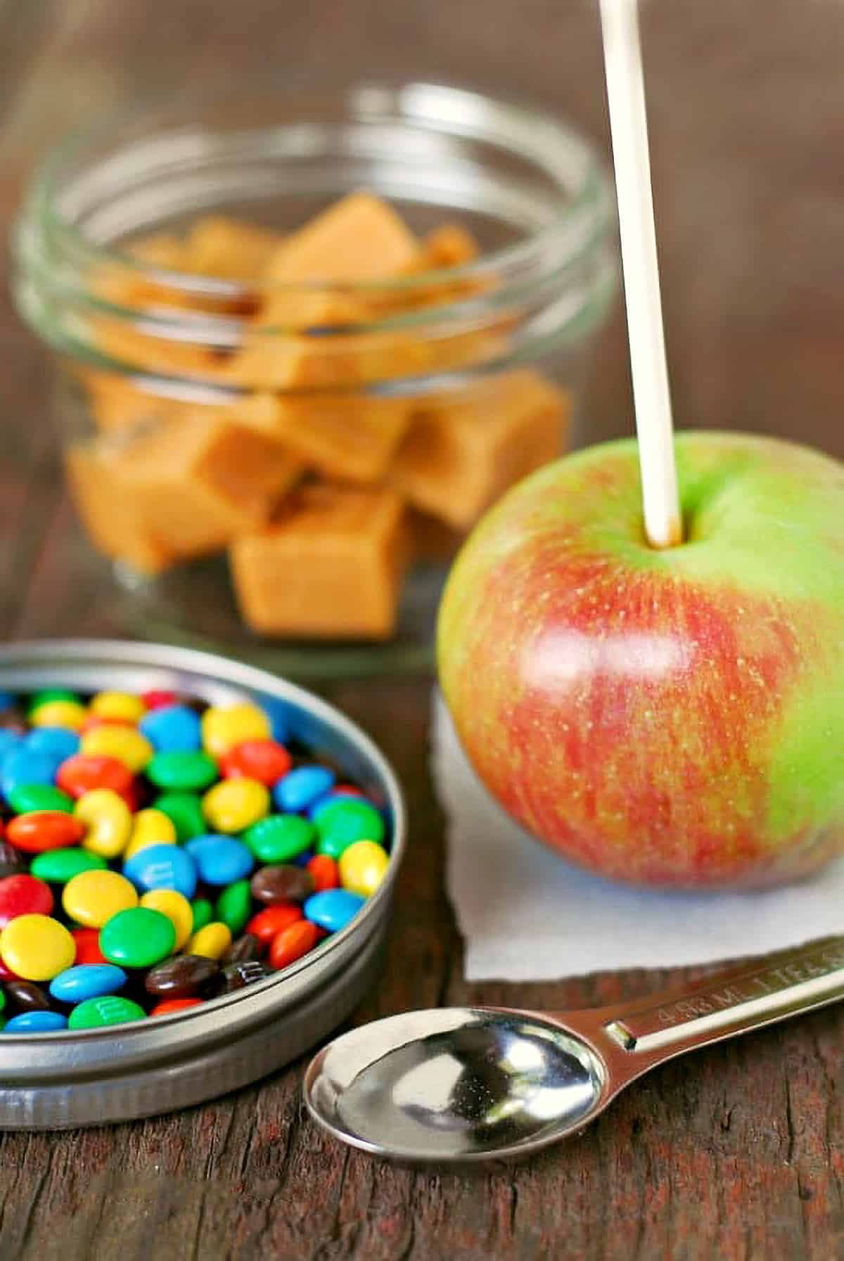 Mini M&M's, caramels in a jar, an apple and a teaspoon of water.