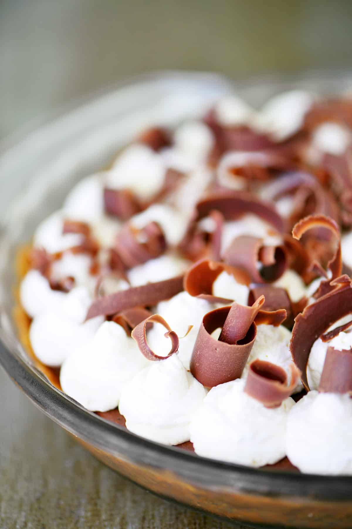 A pie with curled chocolate shaving and whipped cream on top.