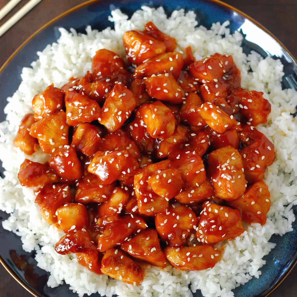 Orange chicken with rice on a blue plate.