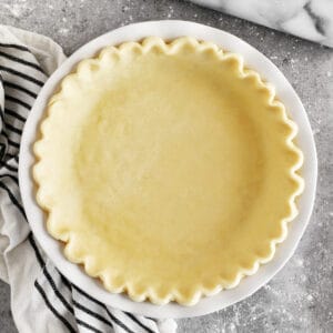 A homemade fluted pie crust in a white baking dish.