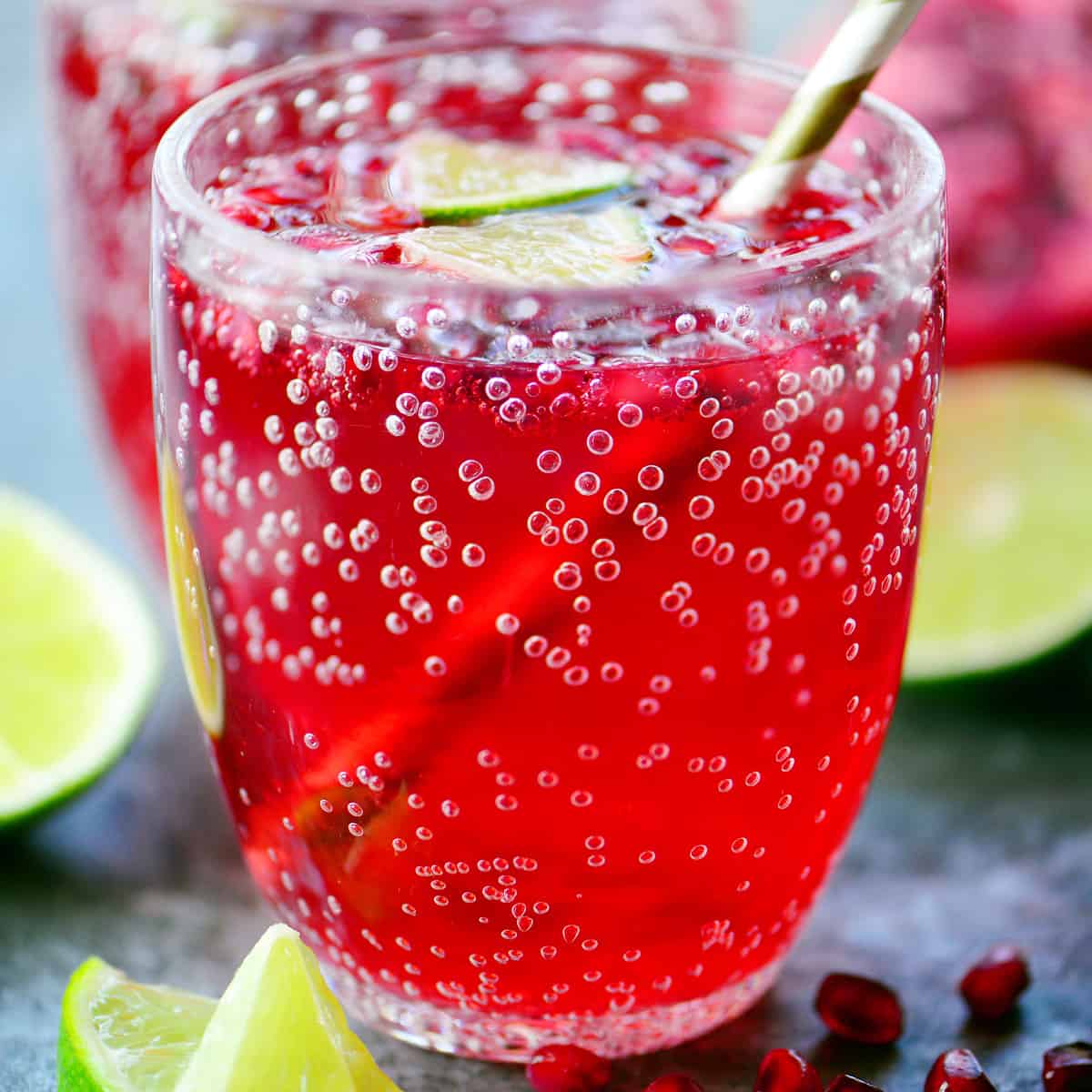 Pomegranate punch in a cup with lime wedges.