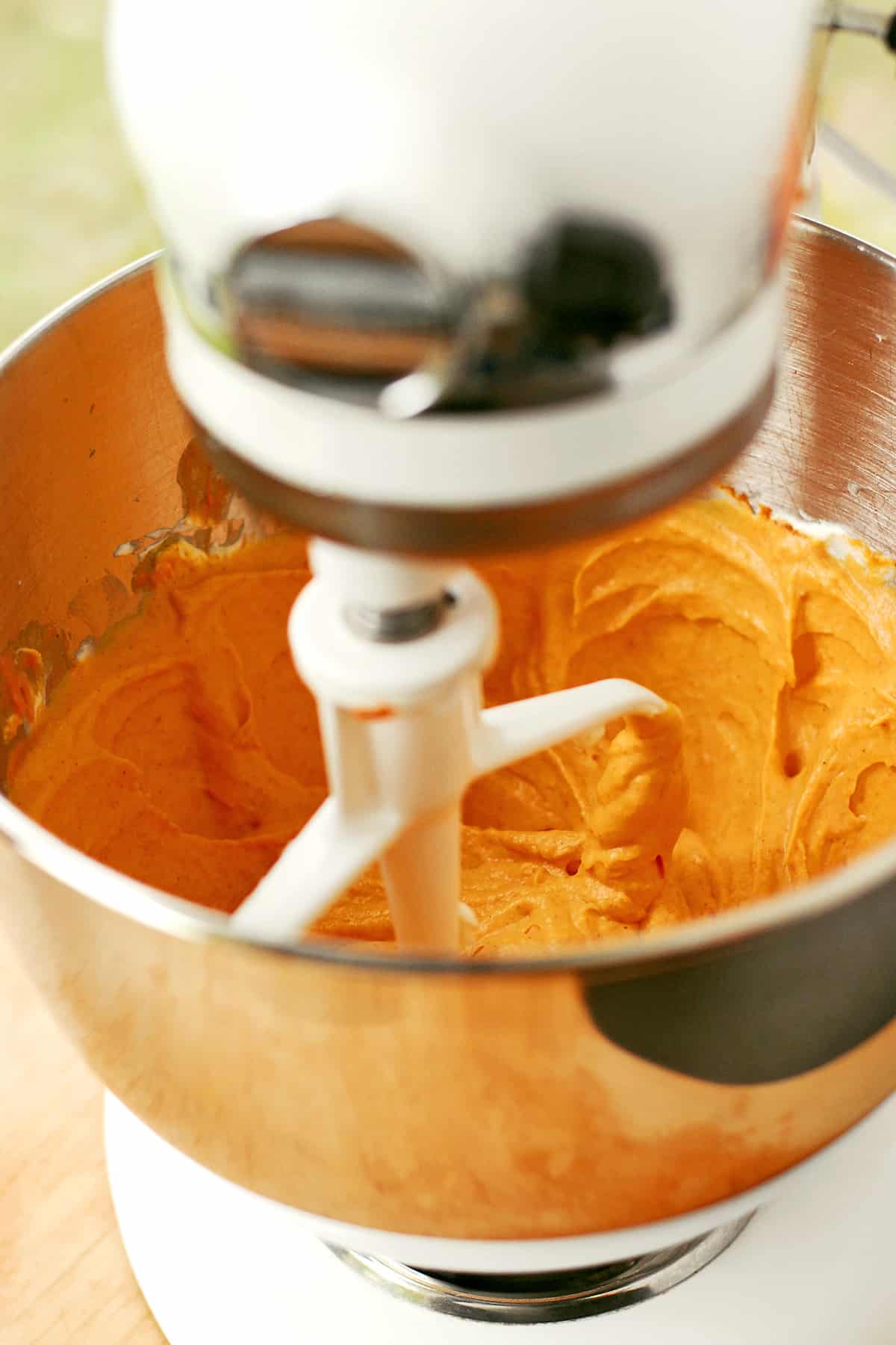 Orange batter in a mixer bowl.