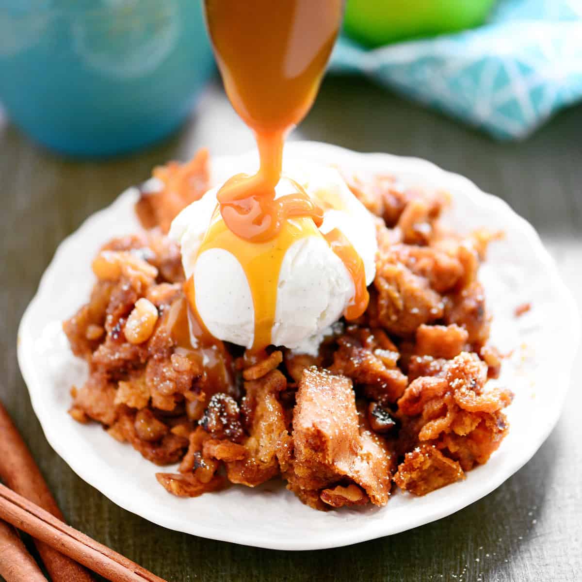 A spoon drizzles caramel on to apple bread pudding.