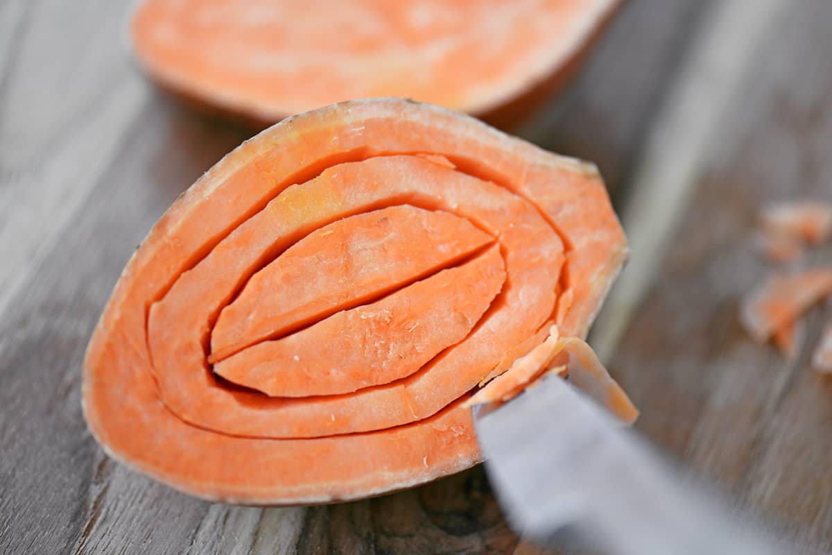 A knife making circular cuts in a sweet potato.