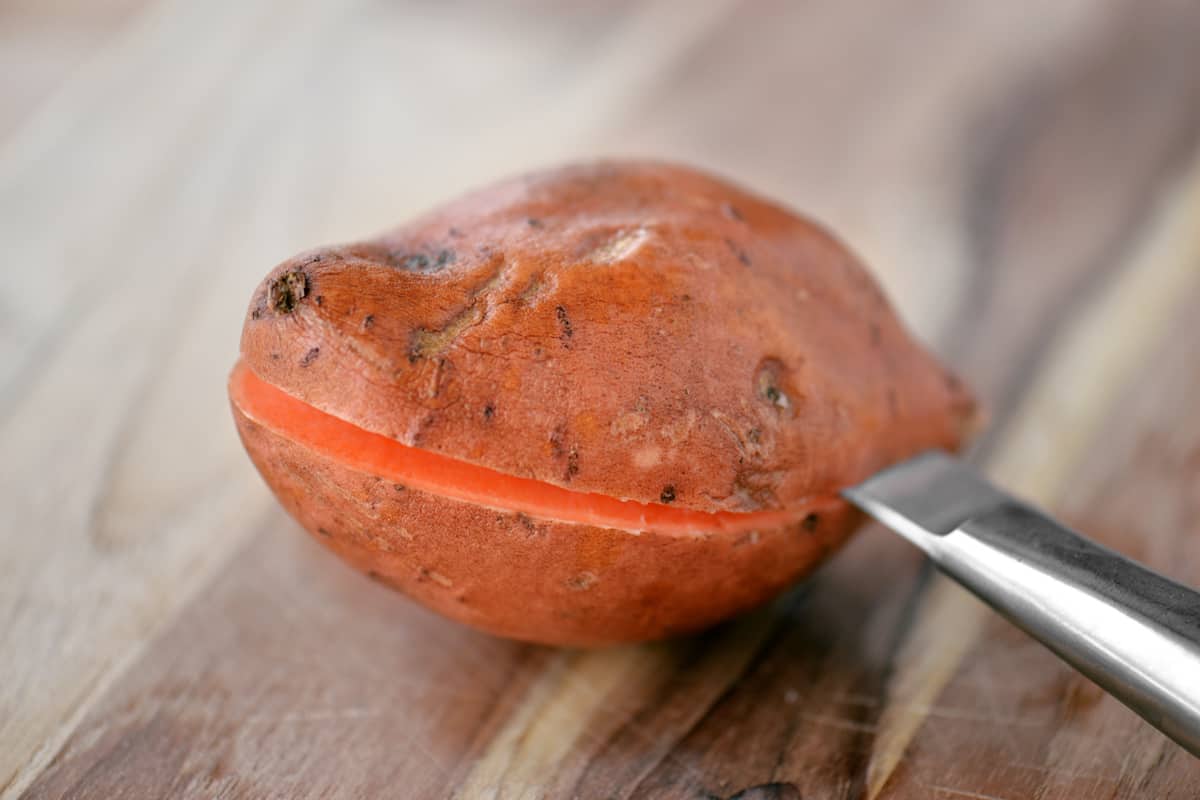 A knife slicing into a sweet potato.