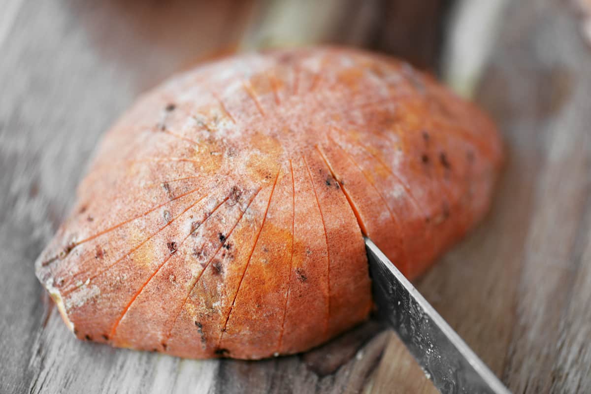 A knife slices a sweet potato.