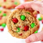 A hand holding a Christmas oatmeal M&M cookie.