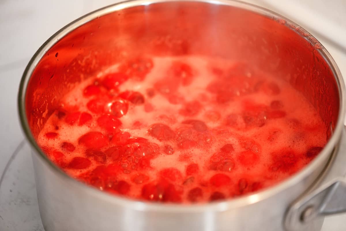 Cranberry sauce boiling in a saucepan.