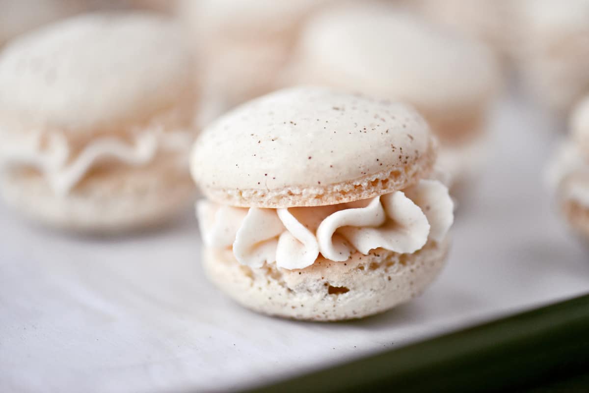 An eggnog Christmas macaron with piped frosting in the middle.
