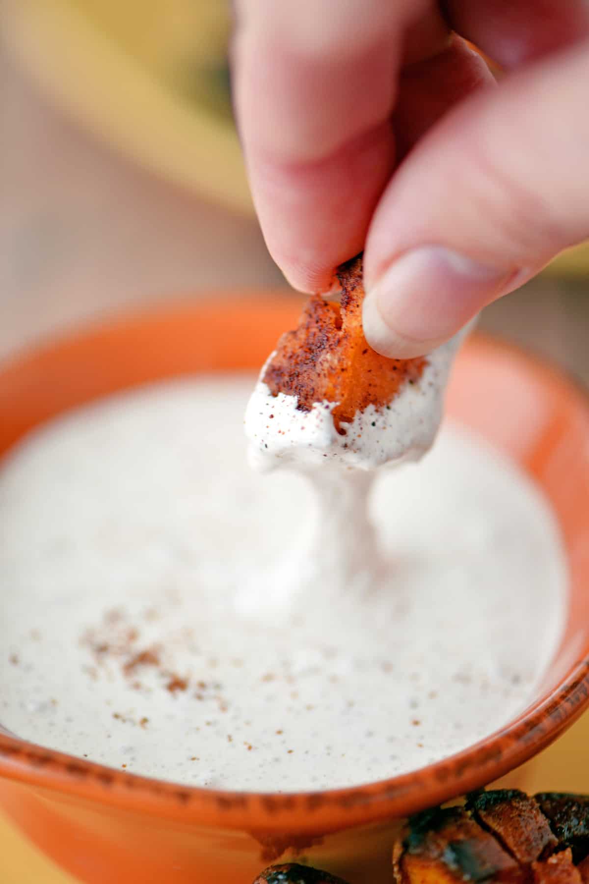 A hand dipping sweet potato into marshmallow cream dip.