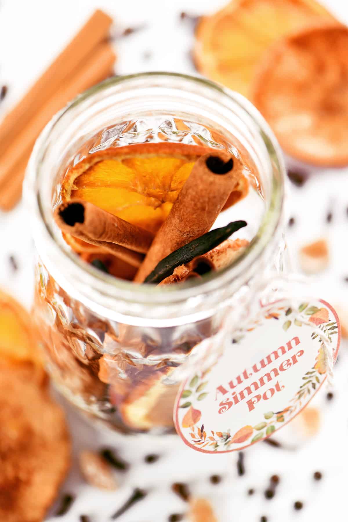 Cinnamon sticks, vanilla and other spices and fruit in a glass jar.