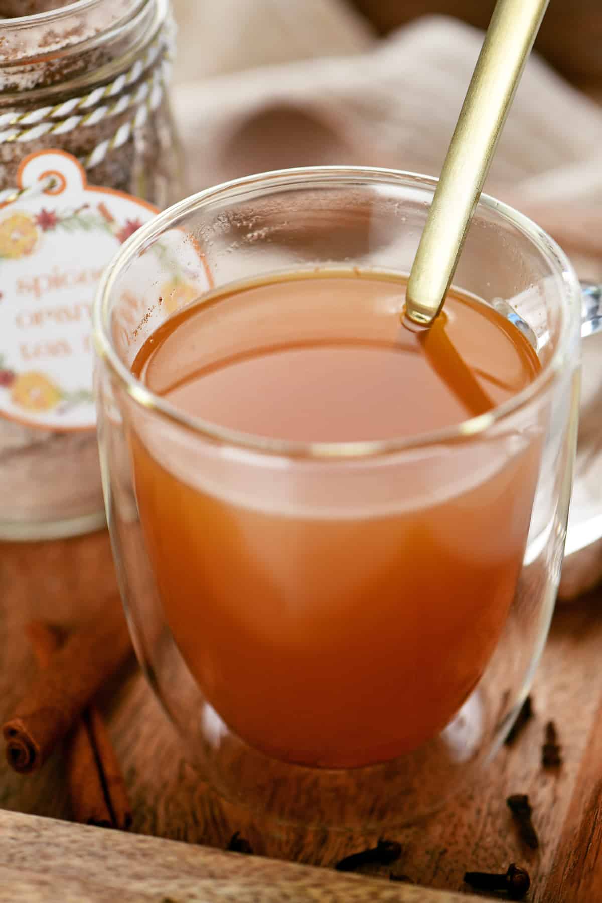 A mug with an orange liquid and a gold spoon.