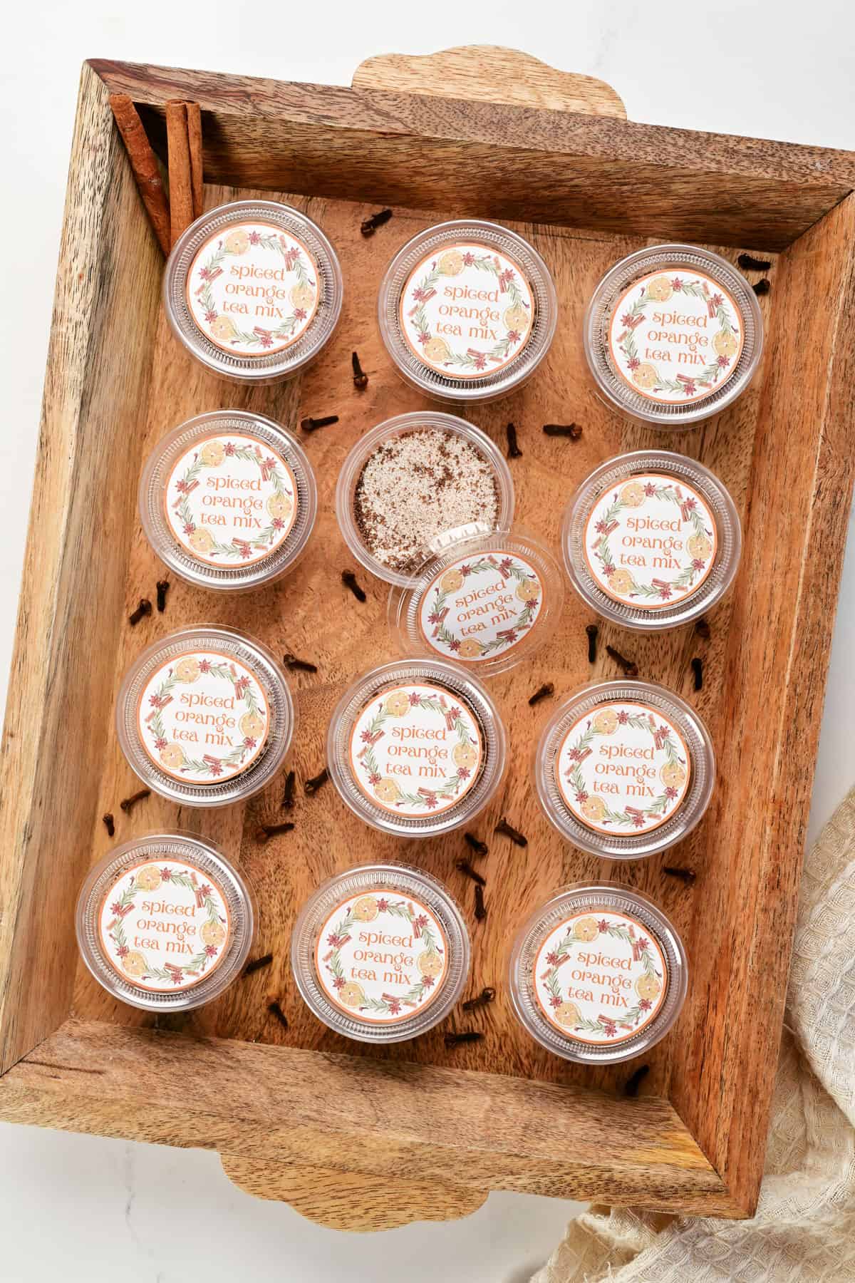 Spiced orange tea mix in containers in a wooden tray.