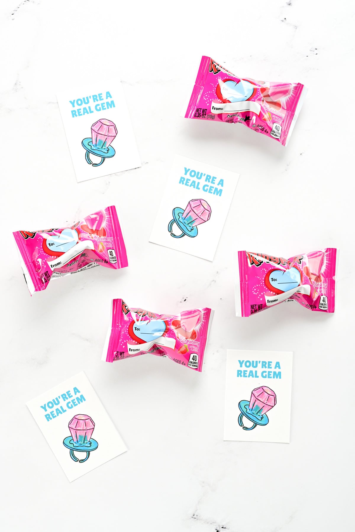 Printable kids valentine cards on a kitchen counter with Ring Pops.