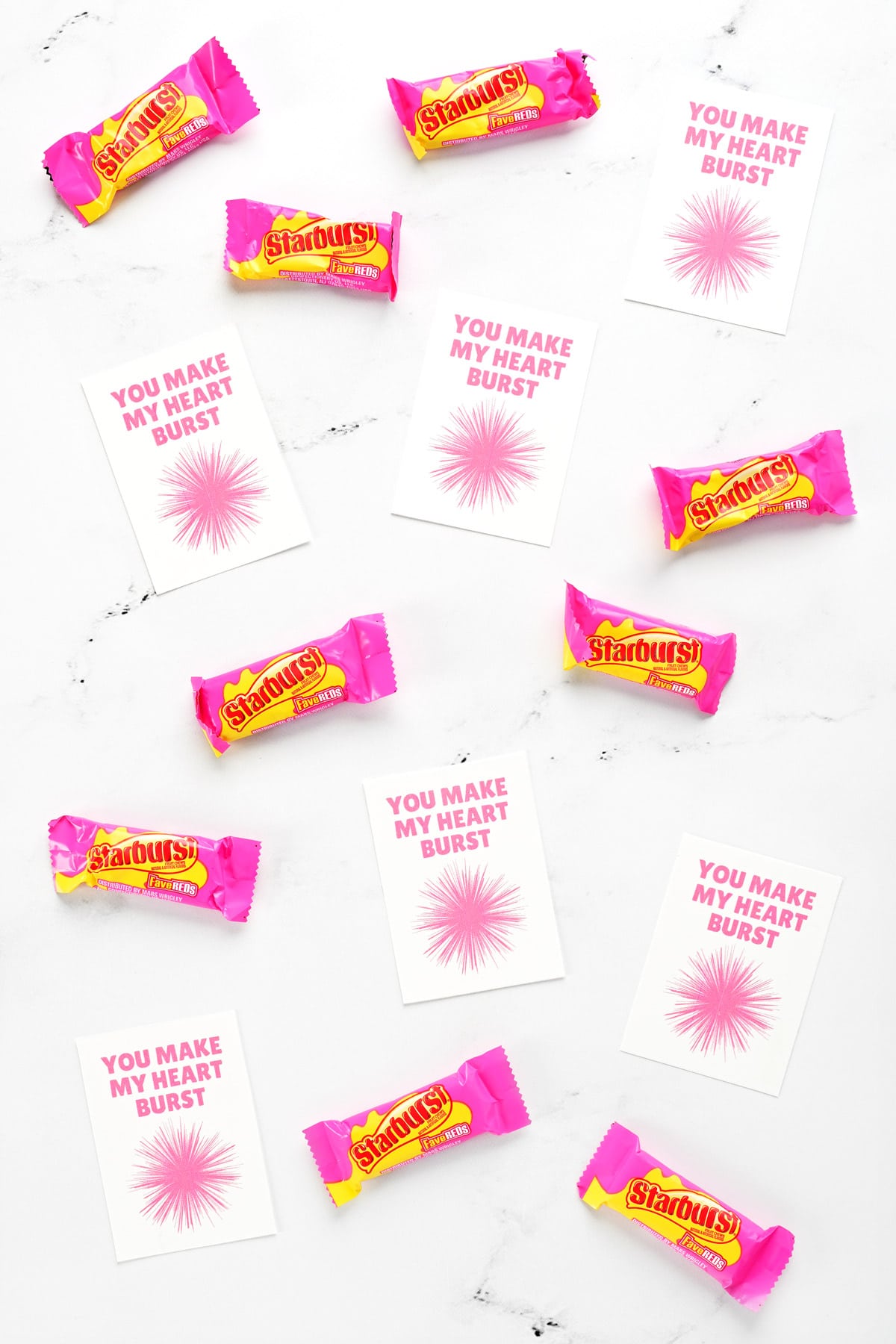 Valentines printables and starburst candies on the surface of a countertop.