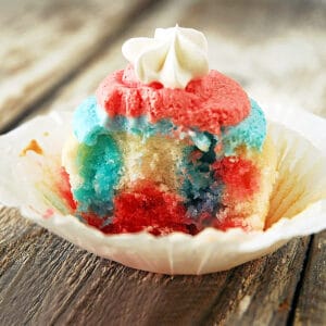 A red, white and blue Jello poke cupcake with frosting on top.