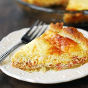 Bacon and cheese quiche on a white plate.