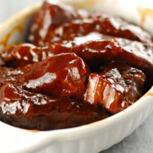 Slow cooker barbecue ribs in a white serving dish.